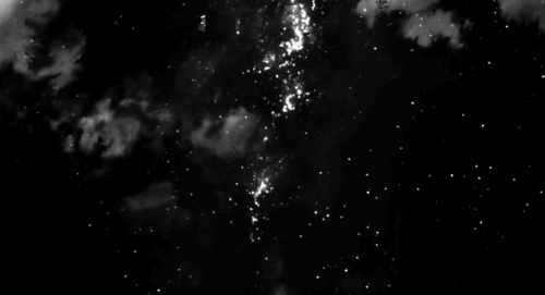 Un fundal cosmic cu stele sclipitoare și nori, într-o animație alb-negru.